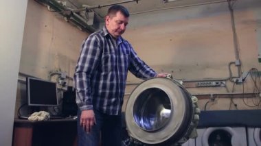 Adam çamaşır makinesini kontrol eder ve çevirir..