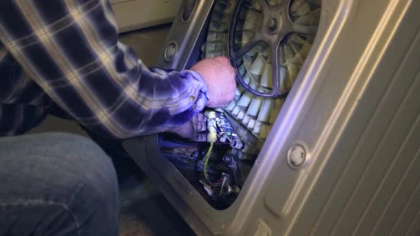 A man reinforces electrical wires inside the washing machine. — Stock Video