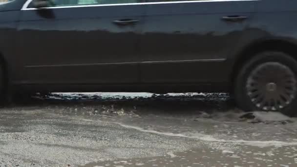 As rodas dos carros estão dirigindo close-up em uma estrada com buracos e poças enlameadas. — Vídeo de Stock
