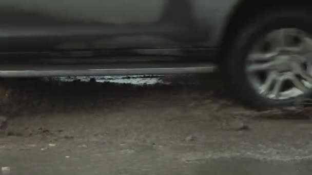 Az autókerekek lassú vezetése rossz úton, sáros pocsolyákkal, lyukakkal és repedésekkel — Stock videók