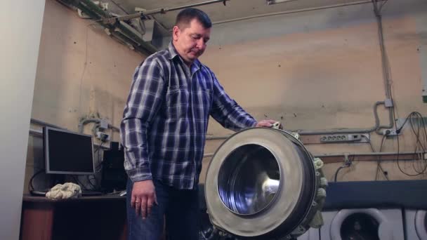 Der Mann kontrolliert und dreht die Waschmaschinentrommel. — Stockvideo