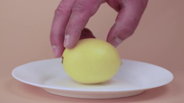 Primer plano manos masculinas poner limón amarillo en un plato blanco. — Vídeo de stock