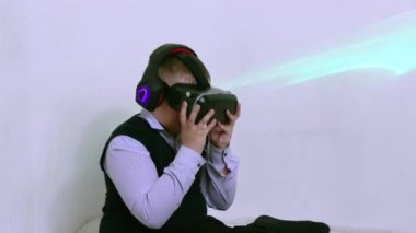 Miğfer takan ve arttırılmış gerçeklik kulaklığı takan bir çocuk gülüp ellerini sallıyor.