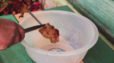 Bir adamın eli şiş bir tabaktan bıçak kebap parçalarıyla kesilir..