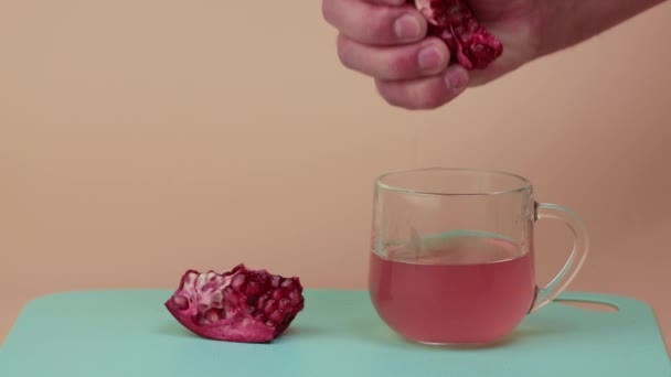 Крупным планом мужские руки раздавливают сок из красного граната в прозрачную чашку. — стоковое видео