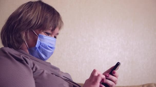 Een vrouwelijke klant in een masker met een smartphone in haar hand doet aankopen — Stockvideo