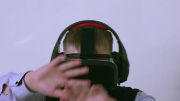 Niño en auriculares de realidad aumentada mirando a la cámara está cubierto por sus manos — Vídeos de Stock