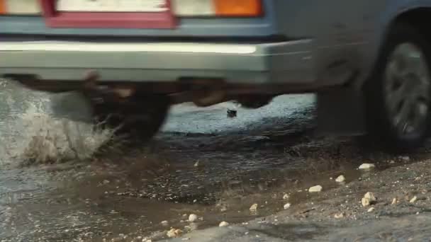 泥だらけの水たまり、穴や亀裂と悪い道で車を運転. — ストック動画
