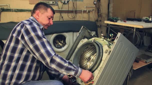 The man inserts the bolts into the holes in the drum of the washing machine. — Stock Video