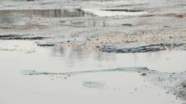 Yakından çekilen arabalar yol boyunca delikler ve çamurlu su birikintileriyle yavaş gider..