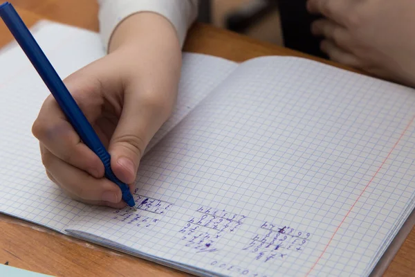 Tükenmez kalemle bir kızın eline yakın çekim. Not defterine numaralar yazıyor..