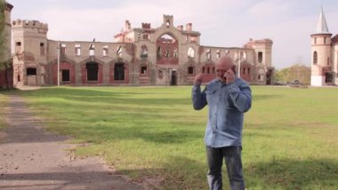 Bir adam telefonda yıkılan bir binanın arka planında konuşuyor..