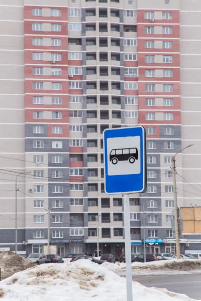 Yüksek bir binanın arka planında otobüs durağı tabelası..