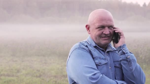 Primo piano uomo che parla al telefono nella nebbia. — Video Stock