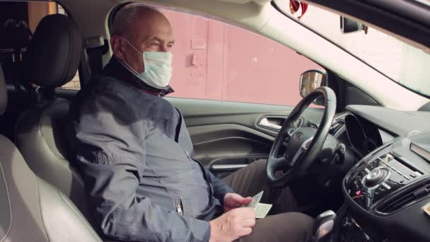 Gelukkige man met een masker achter het stuur telt dollars. — Stockvideo