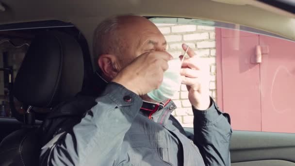 車の中に座っている年齢のビジネスマンが青い医療マスクをつけている. — ストック動画