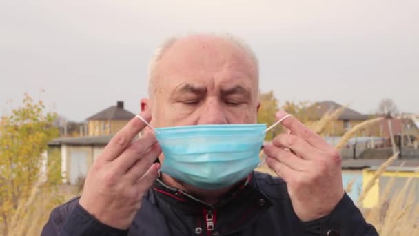 A close-up business man puts on a medical blue mask. — Stock Video