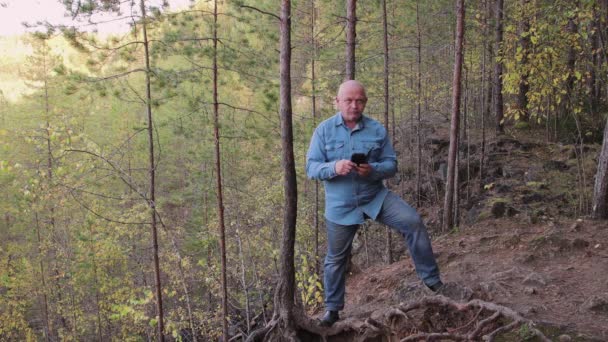 Een man staat op een helling en fotografeert zichzelf als souvenir.. — Stockvideo