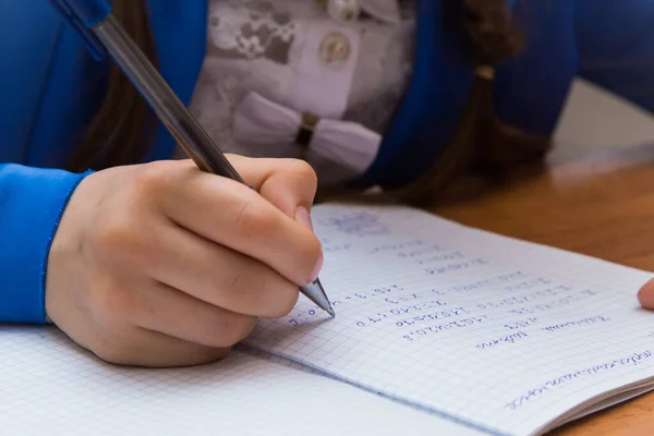 Крупный план руки девушки шариковой ручкой пишет в блокноте. — стоковое фото