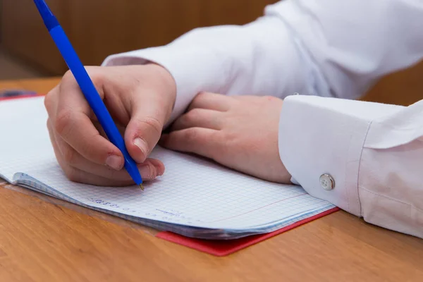 Erkeklerin eli tükenmez kalemle yakın plan bir kafesteki ızgara kağıdına yazıyor.