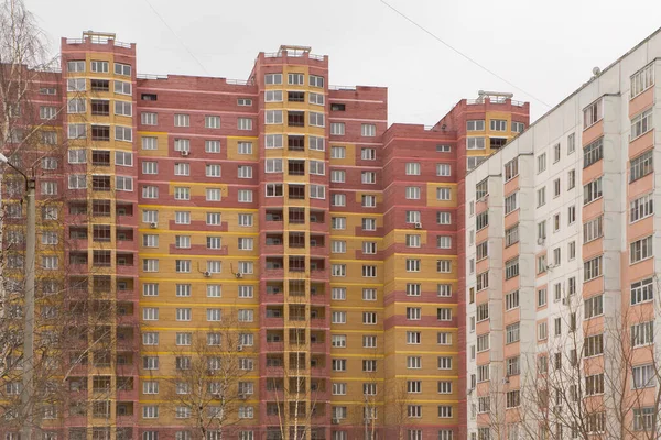 Edificio nuevo de gran altura con balcones rojos junto a una antigua casa gris. — Foto de Stock