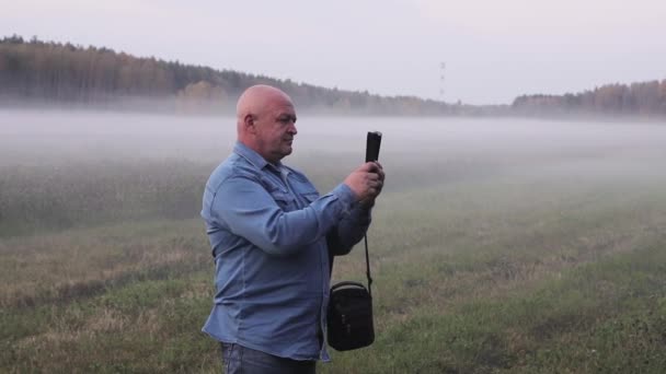 Een man in de mist neemt foto 's van zichzelf als aandenken. — Stockvideo