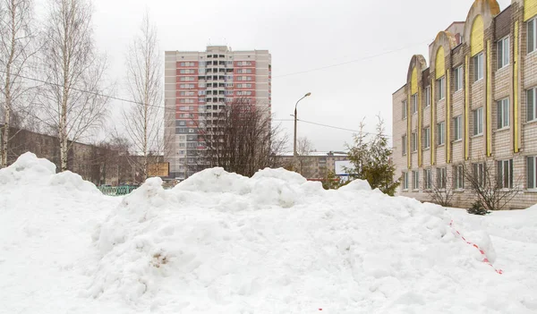 A large snowdrift piled on a city street with high-rise buildings — Stock Photo, Image