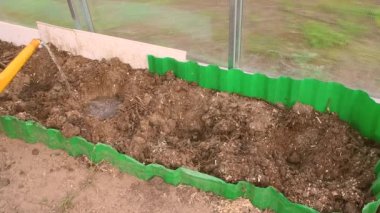 Bir adam su kutusundan, bahçe yatağındaki oyuğa dökülüyor..