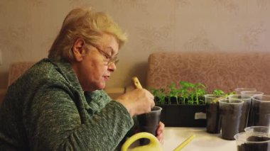 Elinde spatulası olan kadın gübreyi bir tencereye karıştırıyor ve suyla serpiyor..