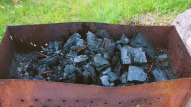 Bir adam ateş yakmak için sıvı döker ve ızgarada kömür yakar.. 