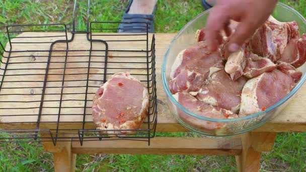 Uma mão de homem coloca pedaços de carne de porco fresca para churrasco no rack de arame. — Vídeo de Stock