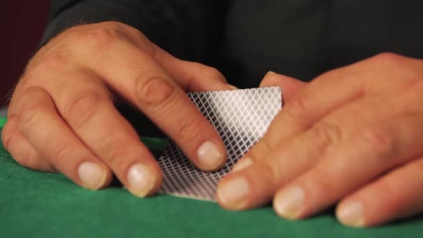 En riskabel pokerspelare i närbild tittar långsamt på sina kort. — Stockvideo
