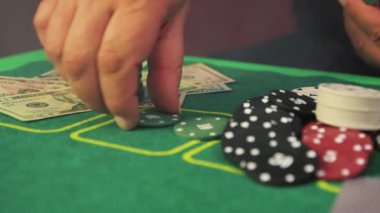 Riskli bir poker oyuncusunun yakın çekim elleri yavaşça yeşil cips topluyor..