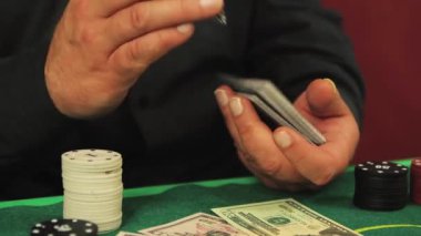 Riskli bir poker oyuncusunun yakın plan elleri bir deste kağıdı yavaşça karıştır. 
