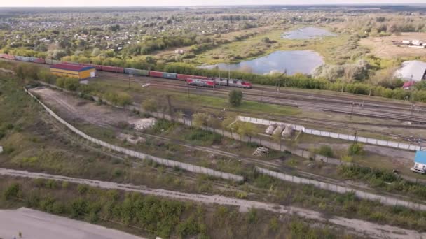 Вид з квадрокоптера на зелені поля, озера та залізницю з поїздом . — стокове відео