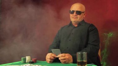 Riskli poker oyuncusu yeşil masada oturur ve bahsi düşünür.. 