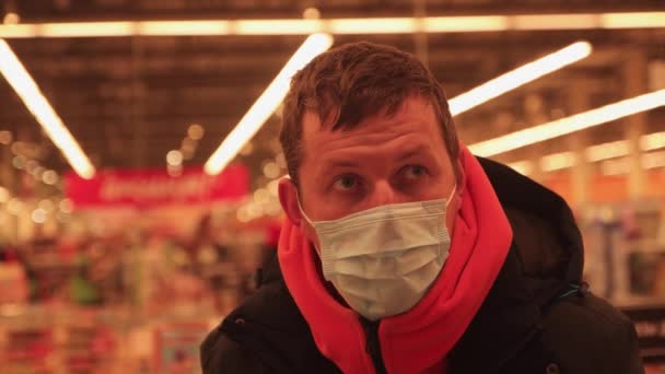 顔を閉じて男の顔は、彼の顔にマスクで、スーパーマーケットで購入を行います. — ストック動画
