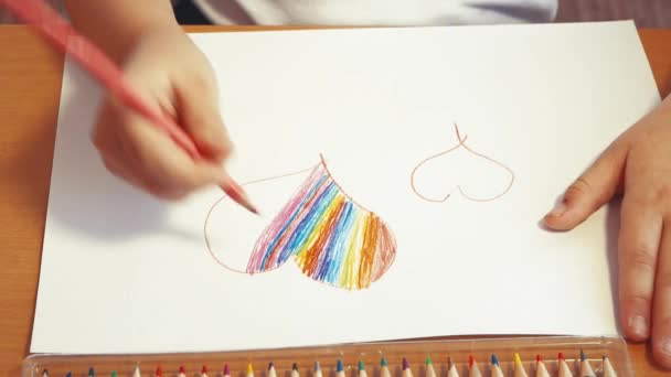 Un coeur arc-en-ciel est dessiné par des mains d'enfants en gros plan avec un crayon de couleur. — Video