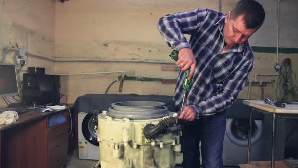 Der Meister montiert die Trommel der Waschmaschine, zieht die Schrauben an. — Stockvideo