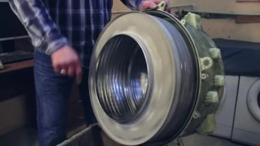 Usta çamaşır makinesinin silinmiş varilini döndürür..