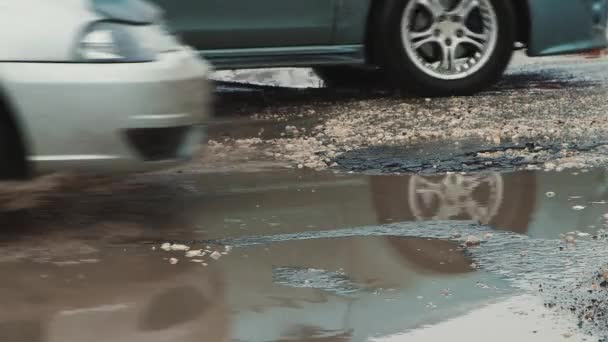 Pfützen und Gruben auf dem Asphalt, beschädigte Straßeninfrastruktur nach Regen. — Stockvideo