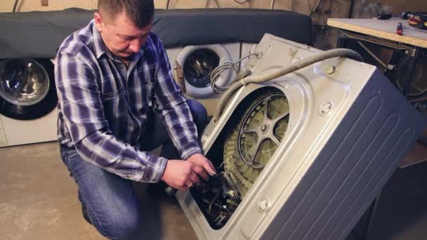 De voorman verwijdert de onderdelen uit de wasmachine. — Stockvideo