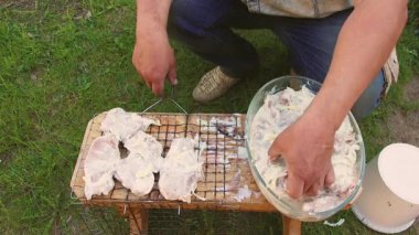 Bir adamın eli, tel askıda salamura edilmiş et kesiklerini serer..