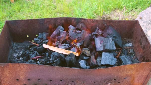O mână de om aprinde cărbunii întinși în grătar . — Videoclip de stoc