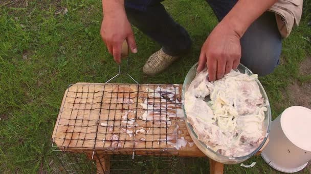 Мужчина кладет маринованные куски мяса на вешалку. — стоковое видео