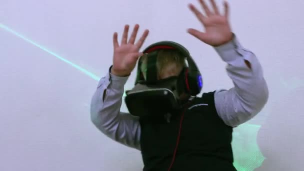 Een jongen in een augmented reality-headset en een koptelefoon danst soepel. — Stockvideo
