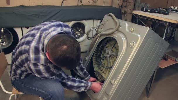 O técnico instala uma nova peça na máquina de lavar roupa. — Vídeo de Stock