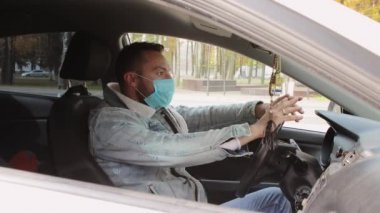 Maskeli modern bir genç adam endişeli, gergin, direksiyonda oturuyor.. 