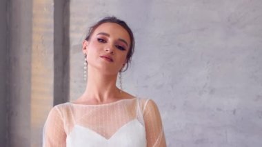 Beyaz elbiseli kız yüzünü çeviren fotoğrafçıya poz veriyor..