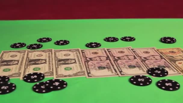 Op de groene speeltafel staan dollarbiljetten en zwarte casino chips. — Stockvideo